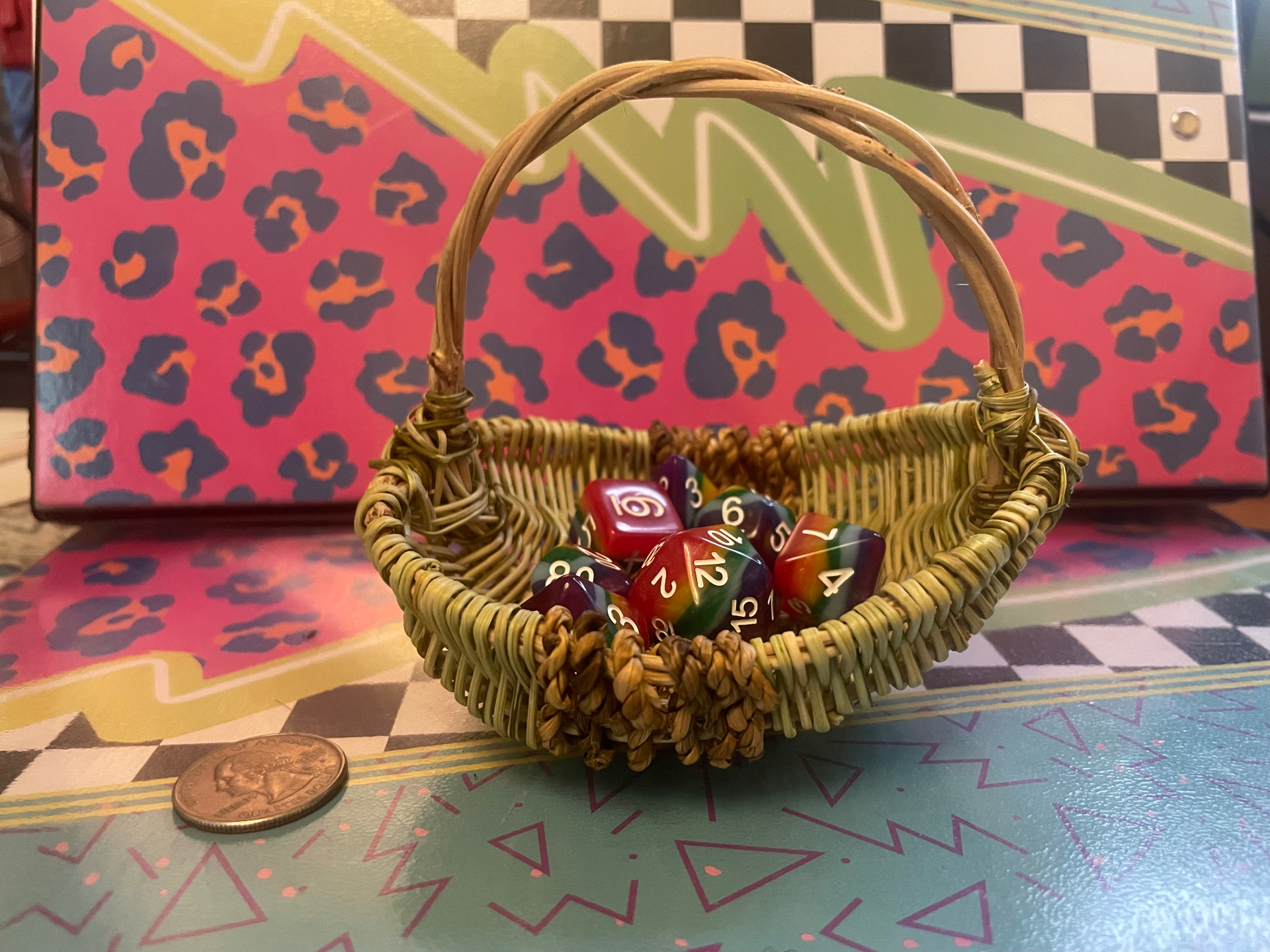 Small kudzu basket holding rainbow dice, with a quarter beside it for scale