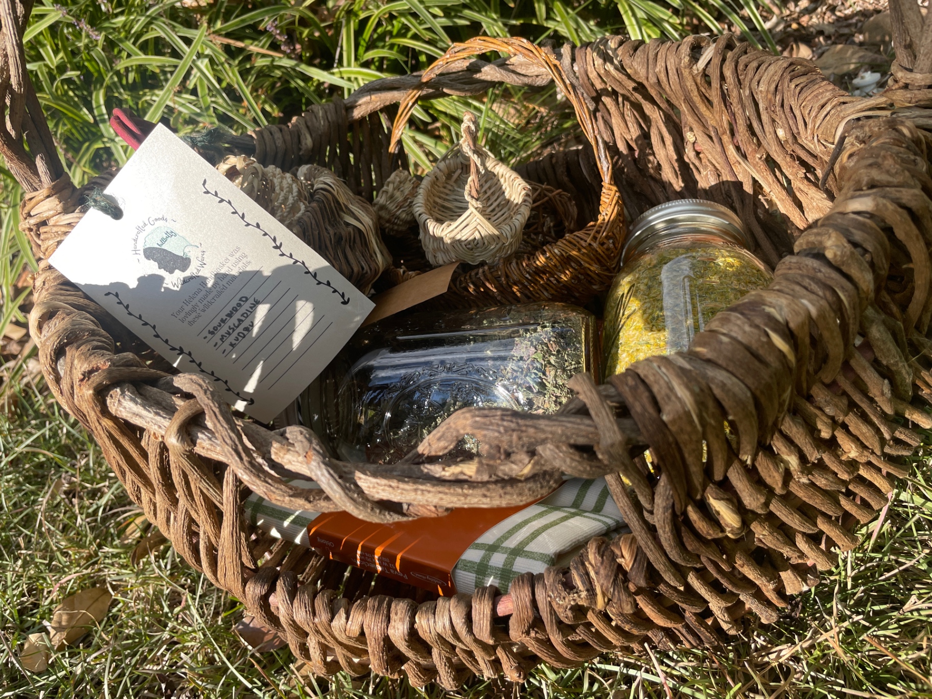 A kudzu basket packed with jars of gathered herbs and a handwritten HillBetty tag